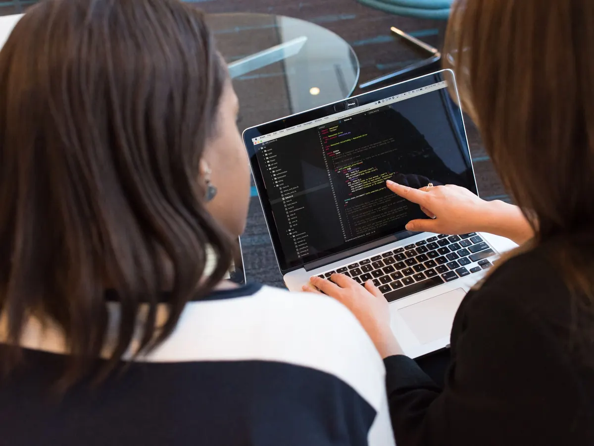 Two engineers reading code on a laptop