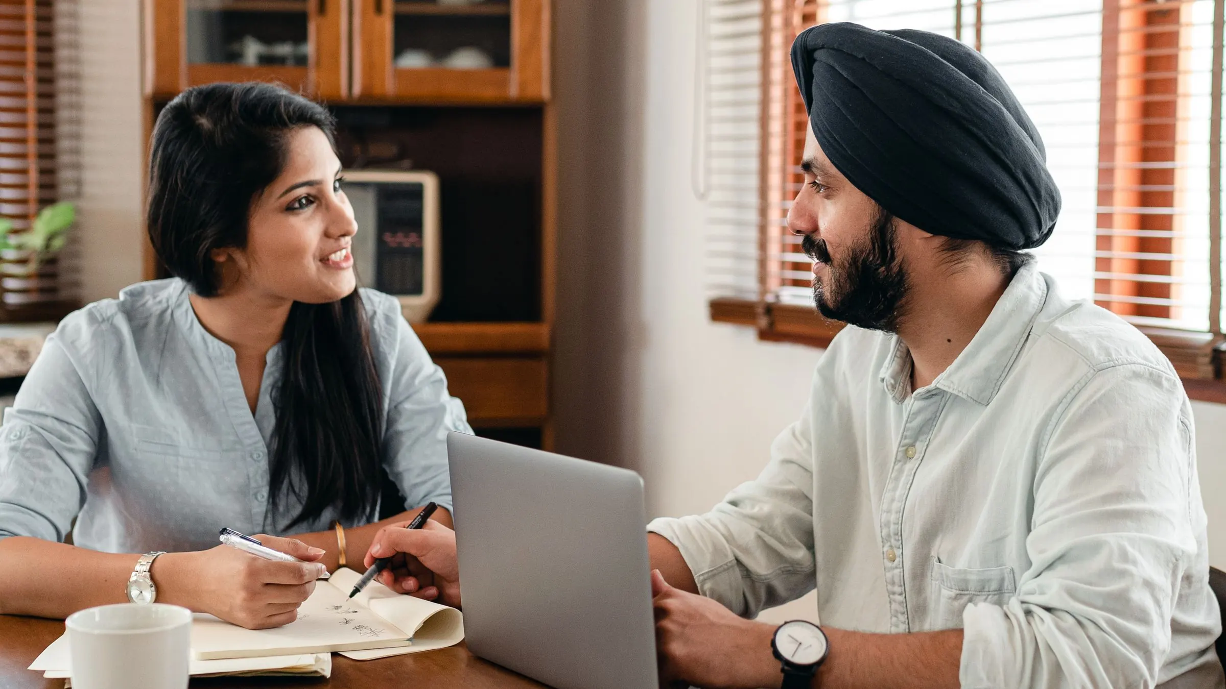 Two colleagues talk through work at a laptop