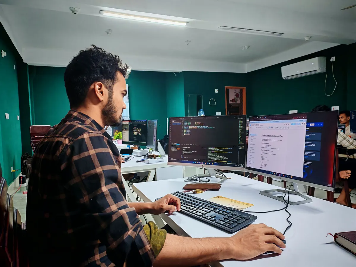 A developer working across two monitors in a bright office