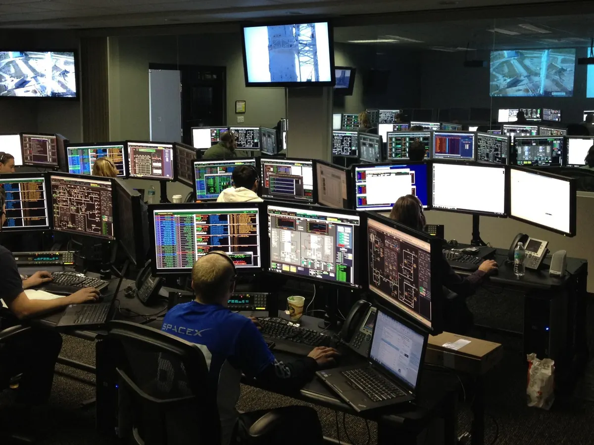 Engineers watching systems on a wall of screens in an operations room