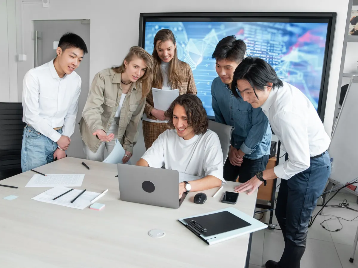 An engineer showing teammates something on his laptop