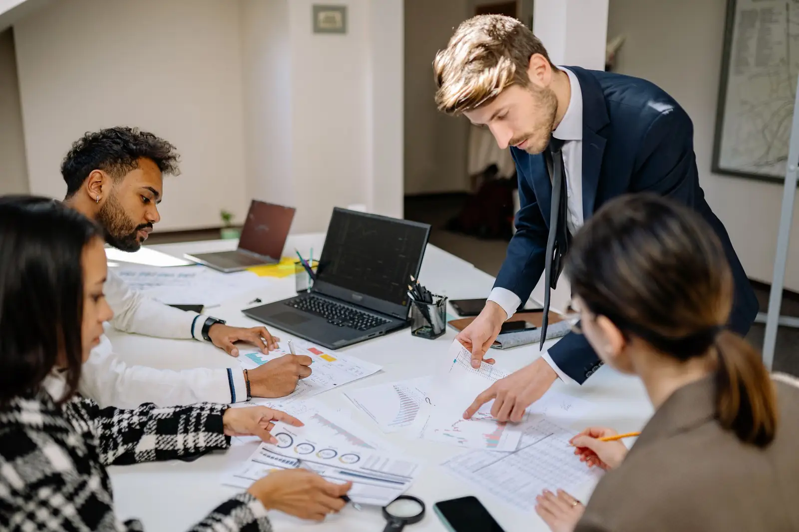 A finance team reviews printed charts and reports together around a meeting table